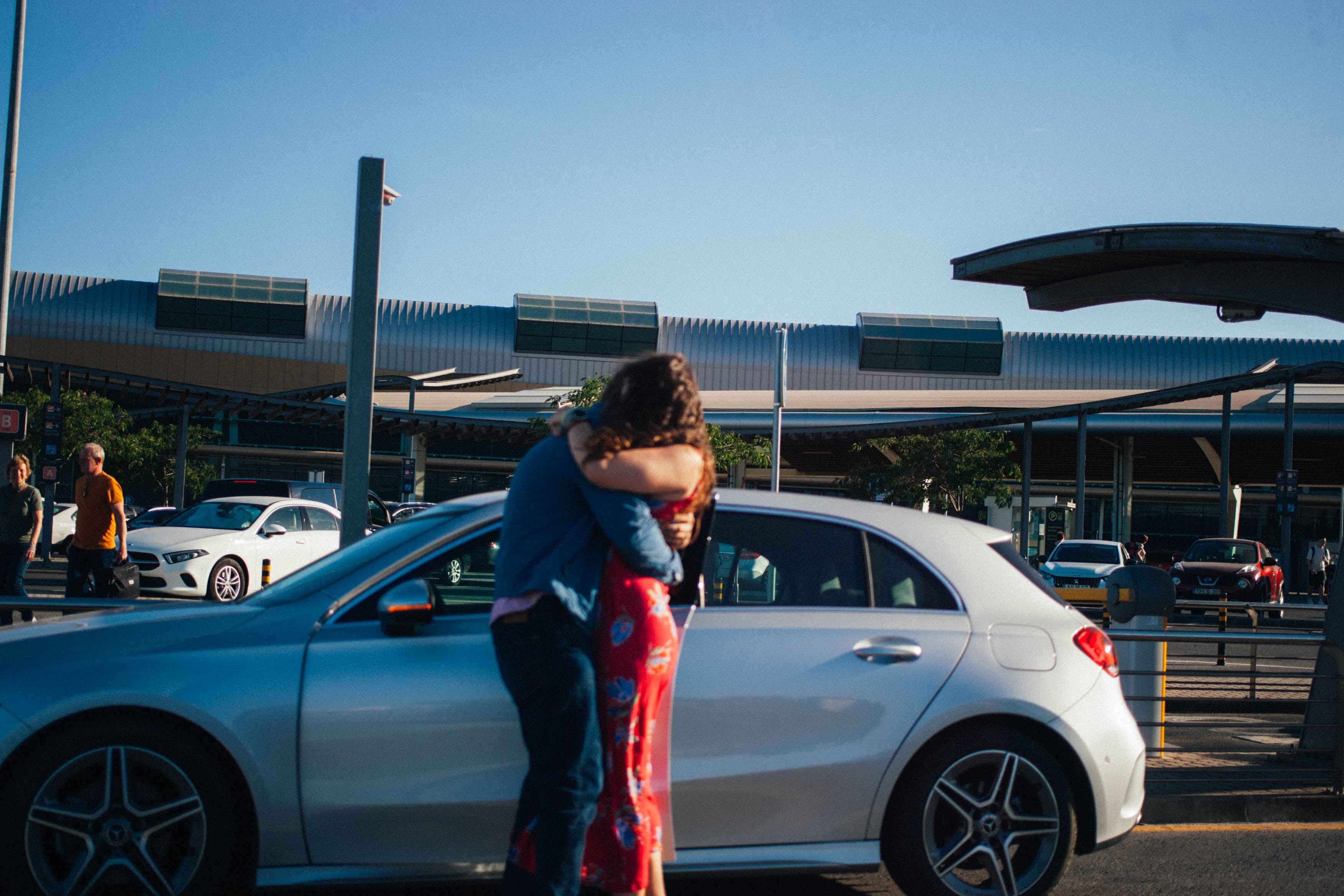 Un couple s’enlace près d’une voiture devant l’aéroport de Faro.