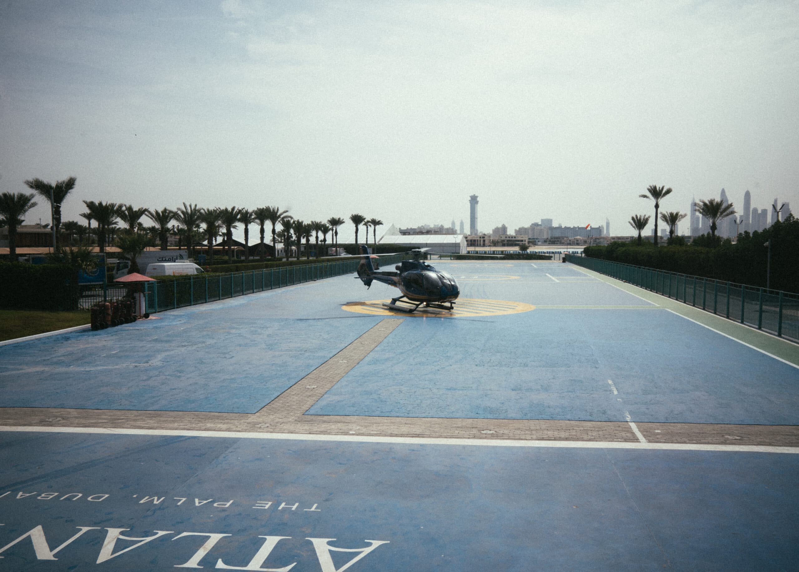 Hélicoptère stationné sur l’héliport d’Atlantis The Palm, avec une vue sur la skyline de Dubaï.