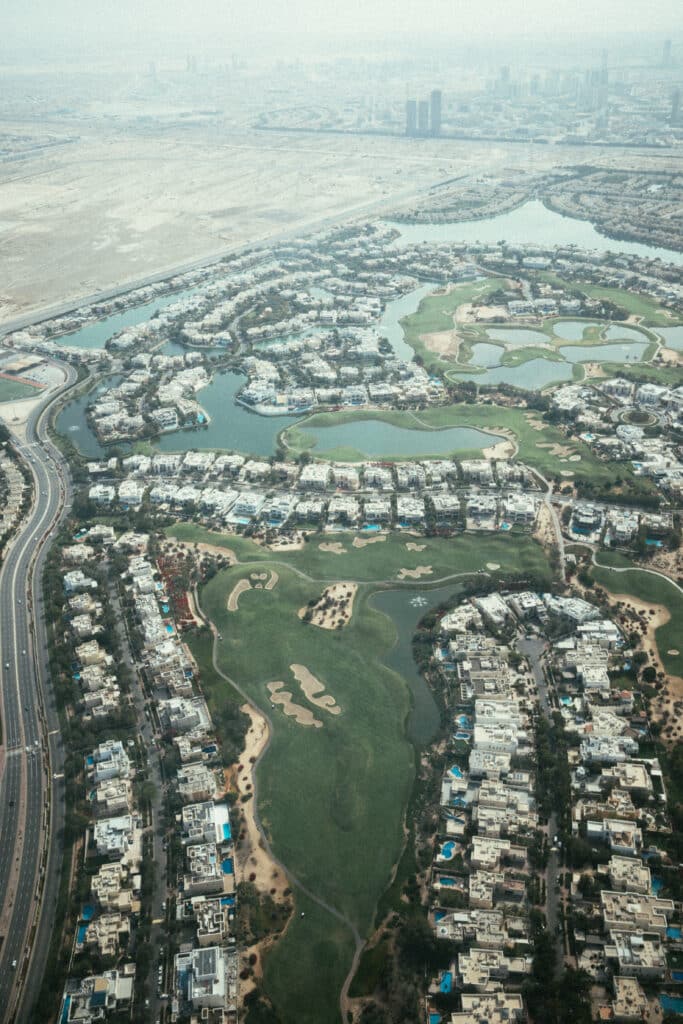 Vue aérienne du parcours de golf de Dubaï, avec la skyline emblématique en arrière-plan.