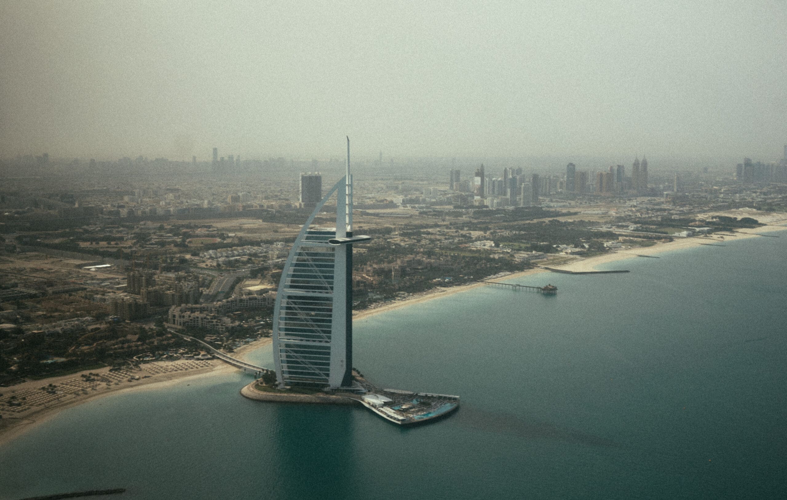 où partir en voyage à dubaï ? Vue aérienne du Burj Al Arab, l’hôtel emblématique en forme de voile à Dubaï, entouré par le Golfe Persique.