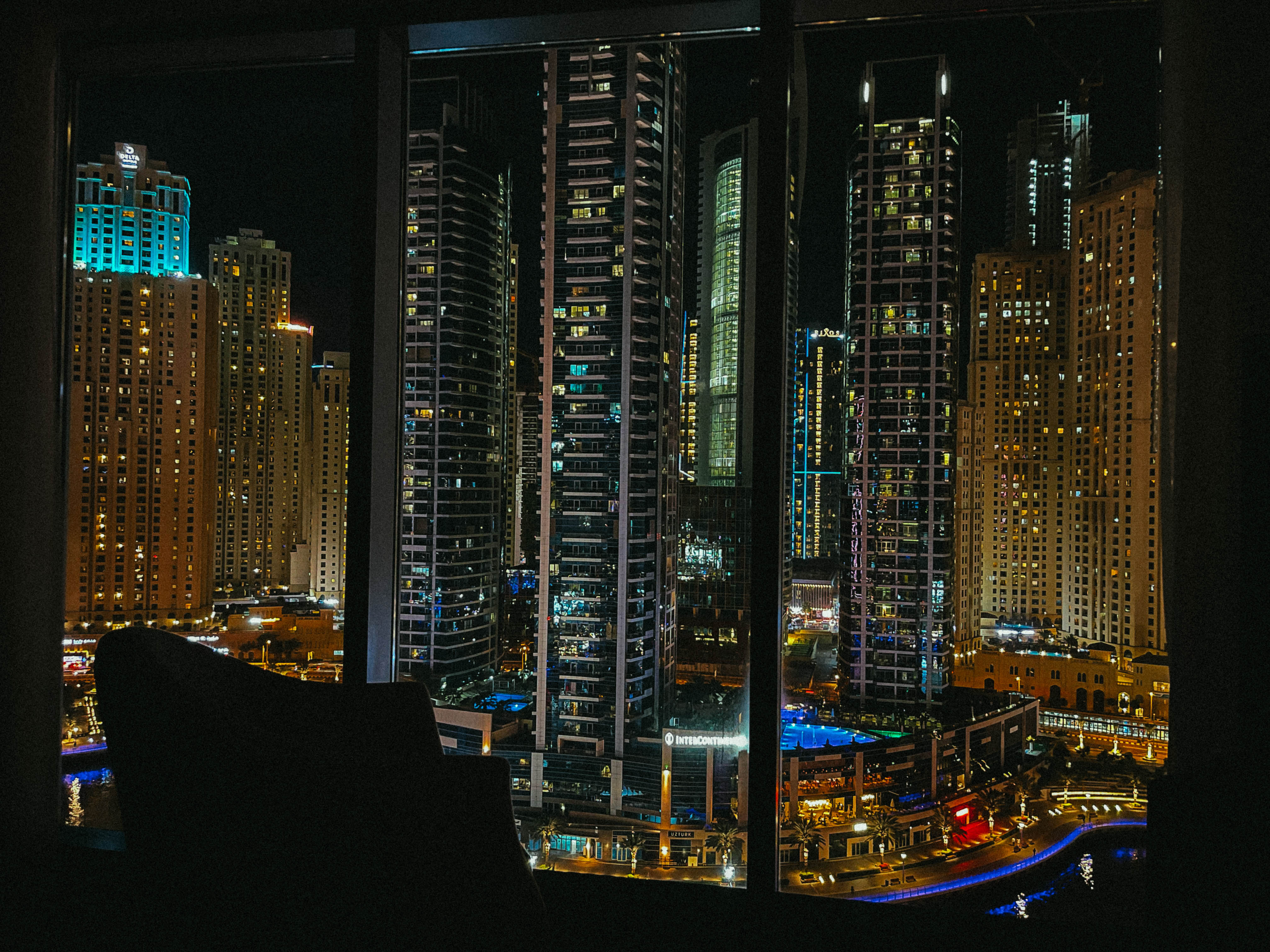 Tours illuminées de Dubaï vues de nuit derrière une baie vitrée.