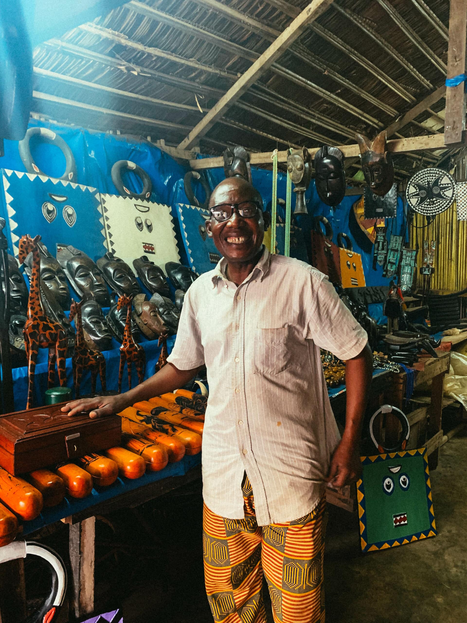 Un artisan souriant vendant des objets d’art et des instruments de musique en Côte d’Ivoire.
