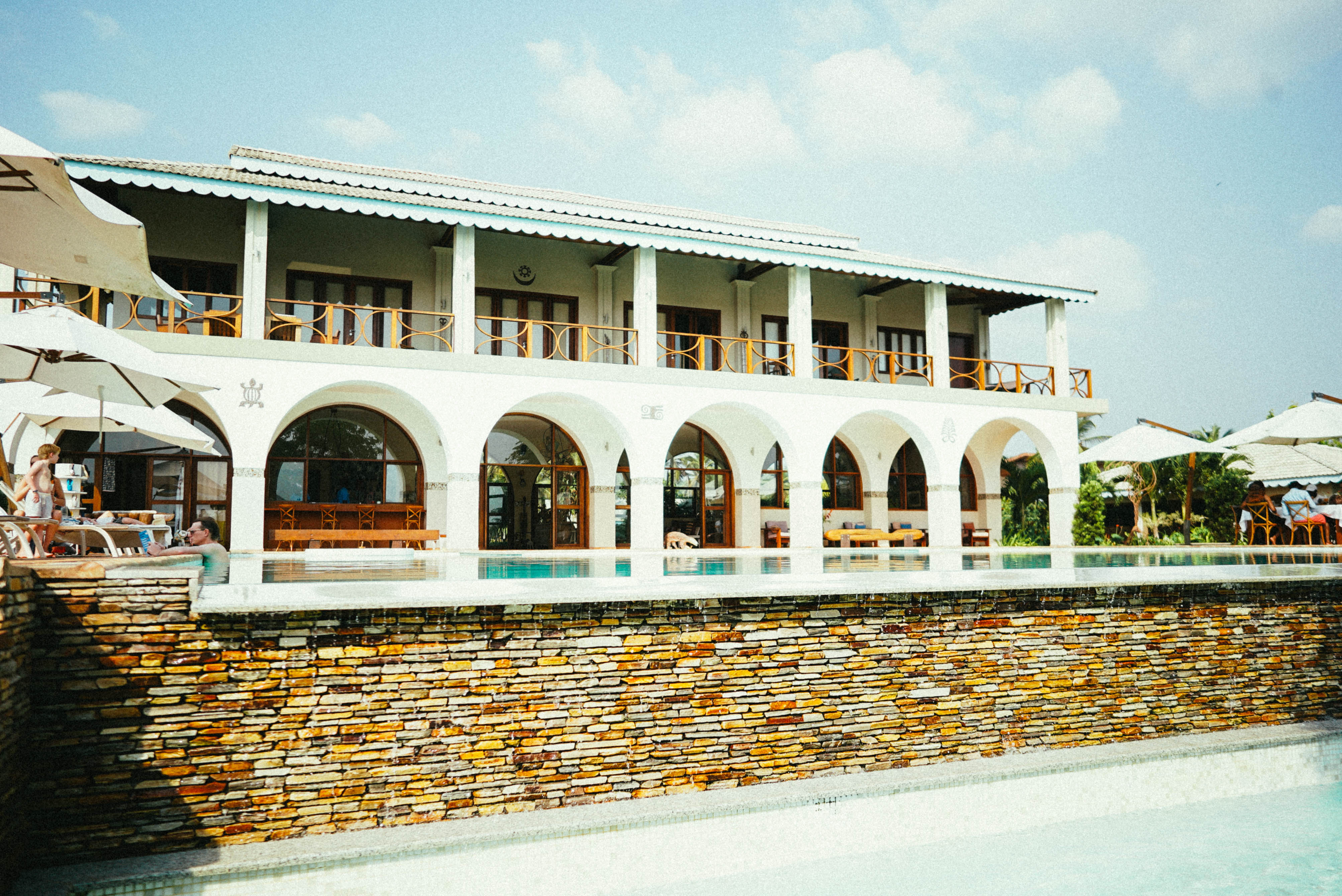 Façade blanche à arches, avec un balcon et une terrasse.
