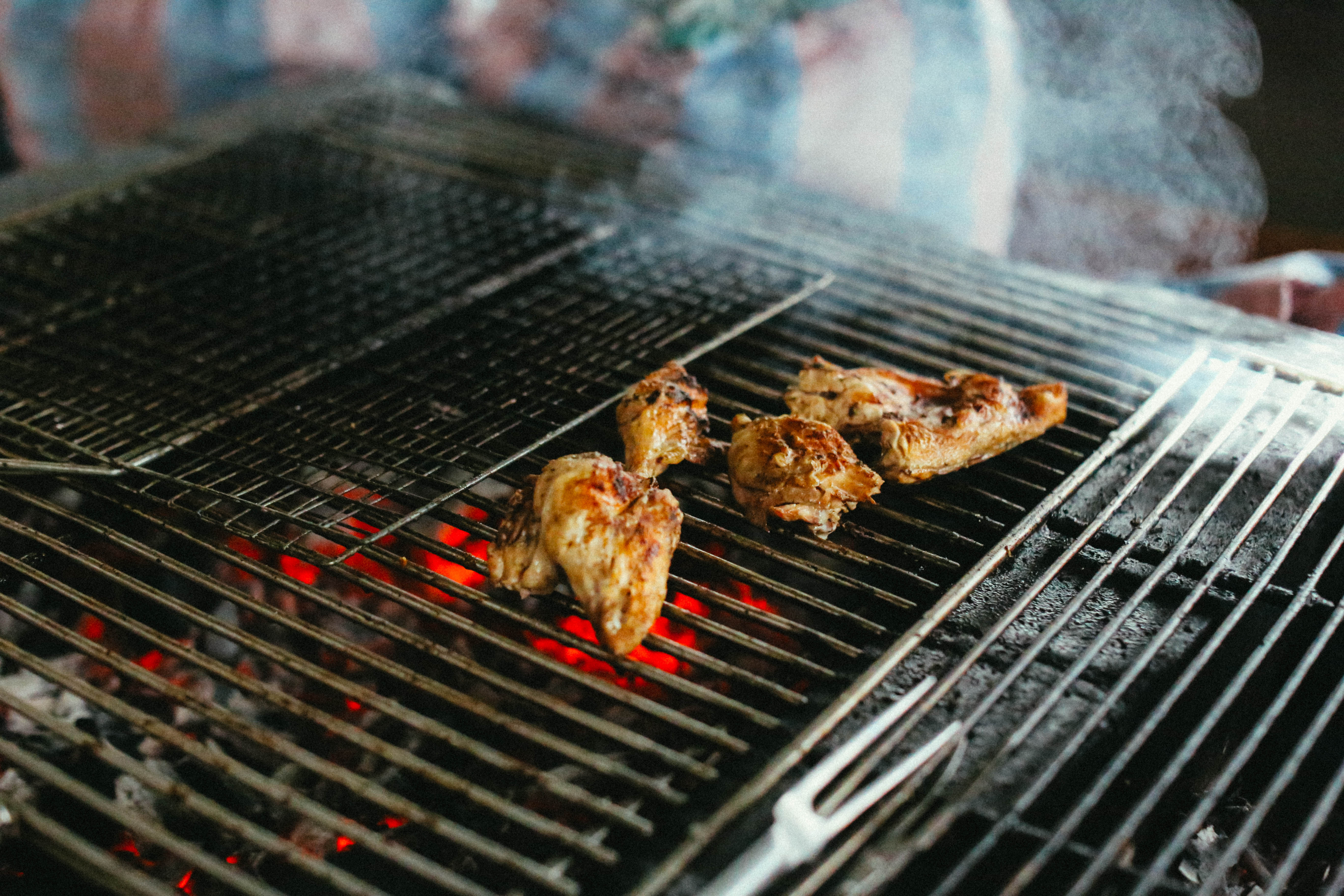 Morceaux de poulet sur un gril au-dessus de braises rouges.