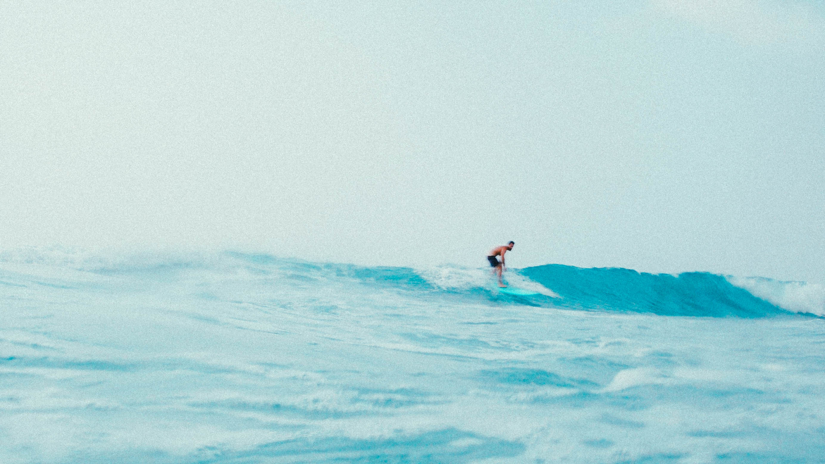Un surfeur sur une vague bleue du littoral ivoirien.