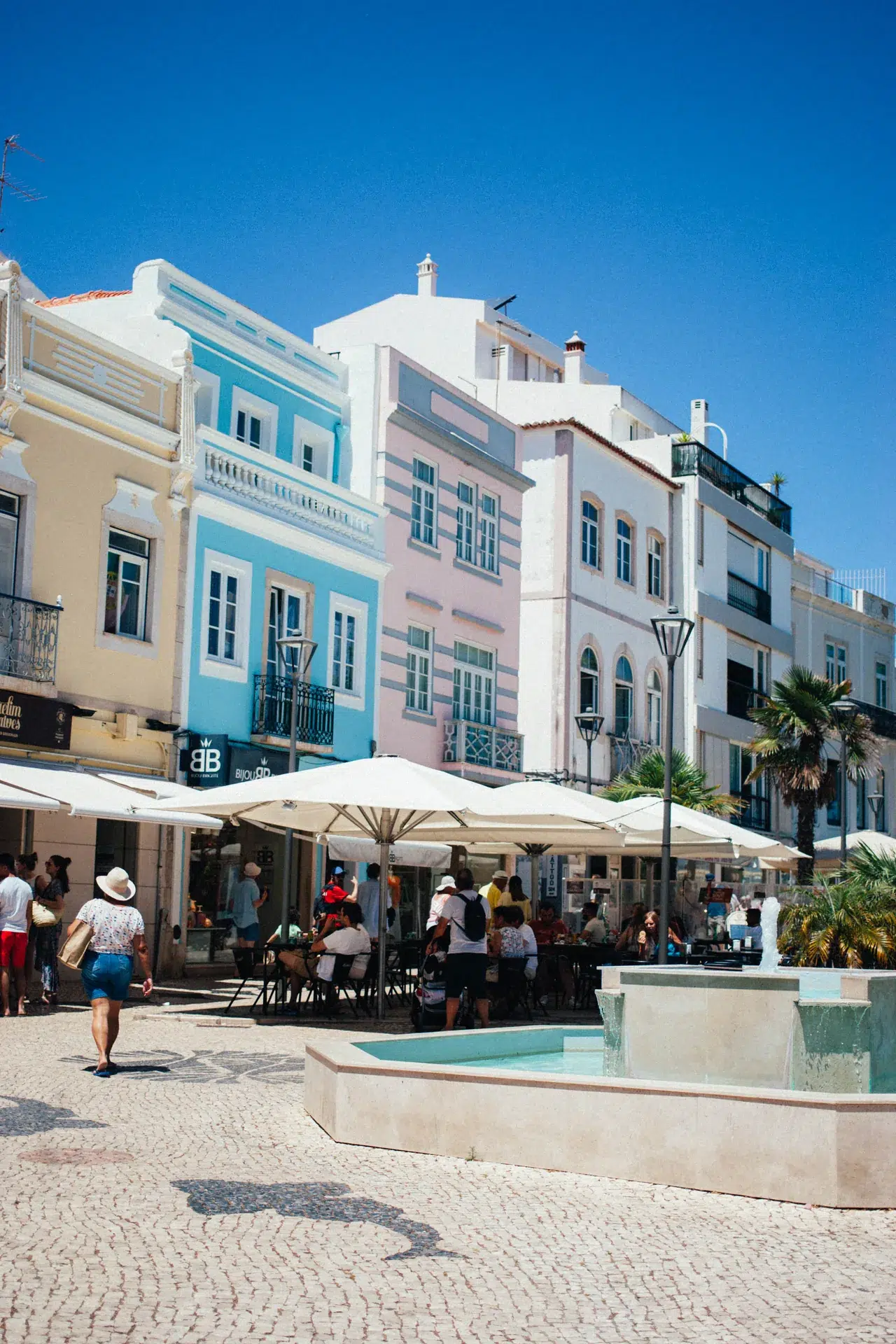 Place de Lagos avec façades pastel, terrasses et pavés à motifs.