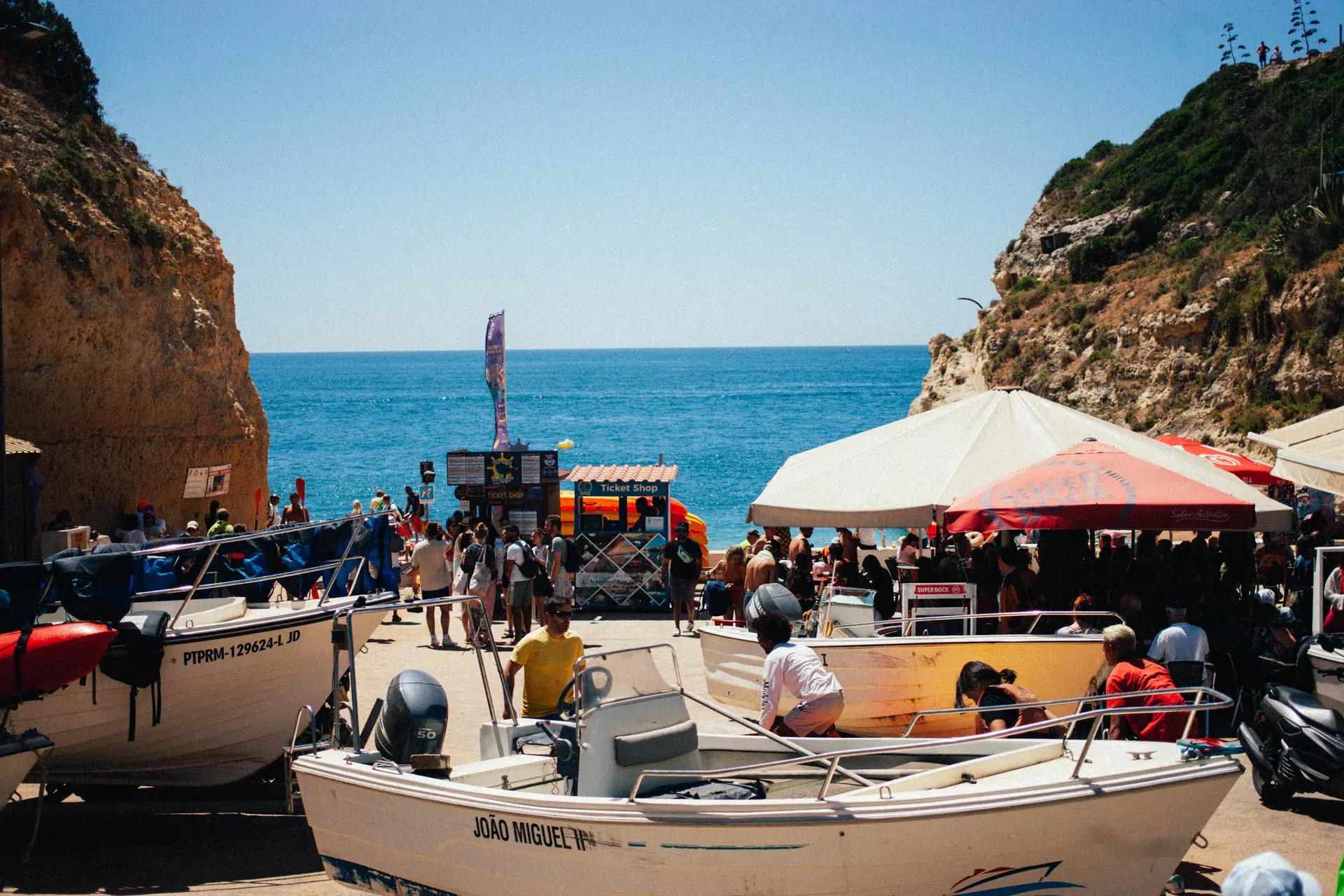 Bateaux d’excursion et visiteurs sur la plage de Benagil entre les falaises.