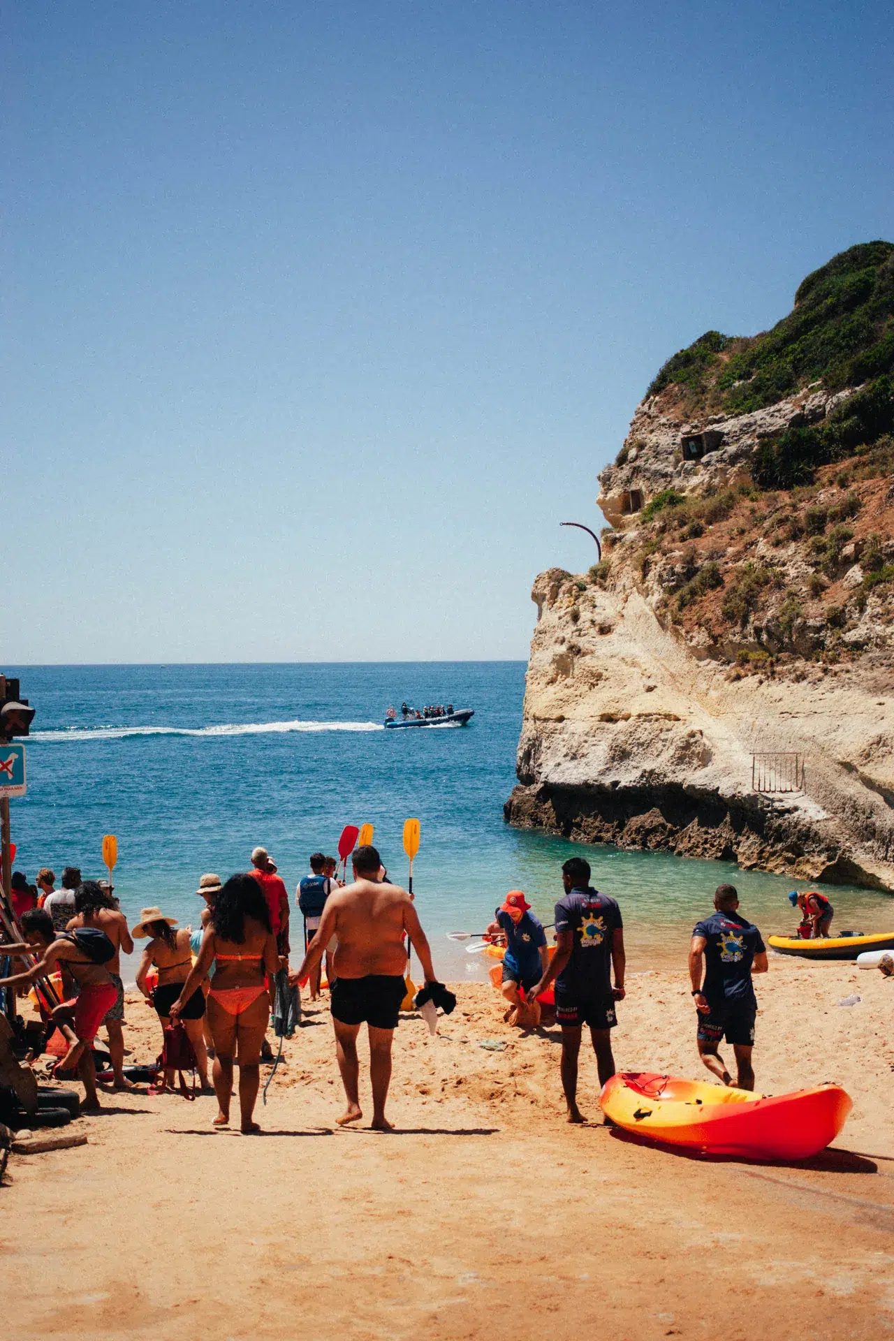 Visiteurs, kayak et bateaux au bord de la plage de Benagil.