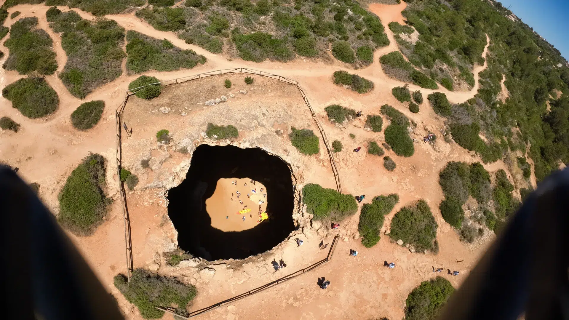 Ouverture de la grotte de Benagil vue d’en haut, avec du sable à l’intérieur.